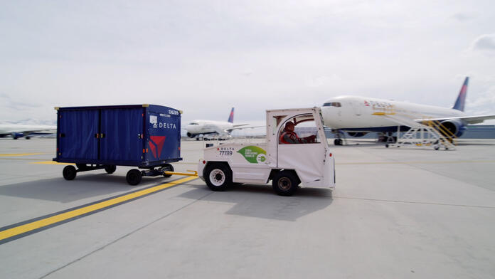 A Delta ramp agent drives an electric bag tractor at Salt Lake City International Airport (SLC).