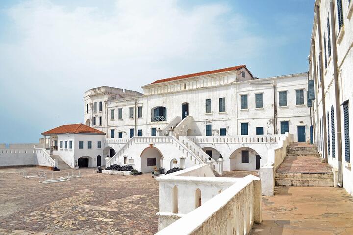 Ghana's Elmina Castle beneath a blue, lightly cloudy sky.